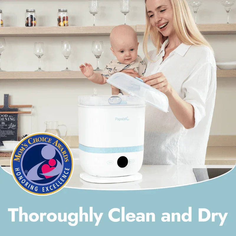 Mother holding baby using Papablic sterilizer in kitchen with Mom's Choice Award badge