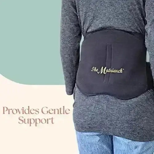 Rear view of black Matriarch pregnancy support belt showing back panel and logo on a model with overlay text Provides Gentle Support