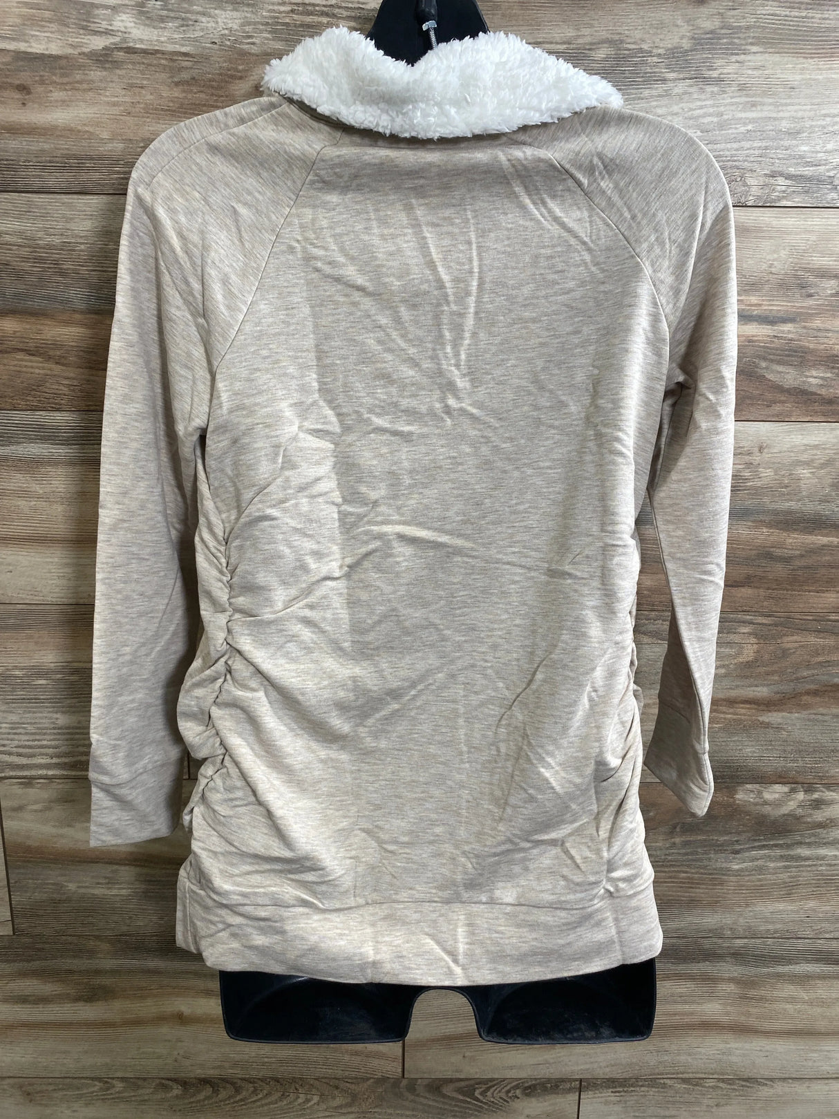 Back view of Isabel maternity oatmeal sweatshirt showcasing white sherpa collar and side ruching with wooden plank background