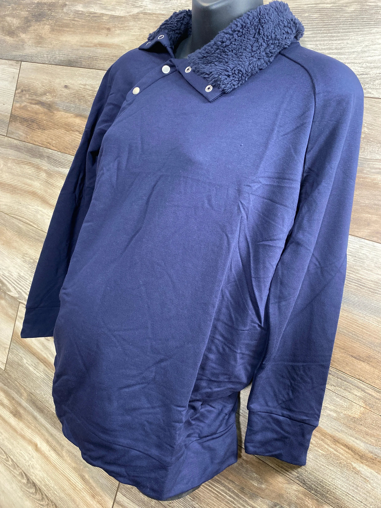 Front three-quarter of navy Isabel maternity sweatshirt with snap sherpa collar on mannequin, wood backdrop