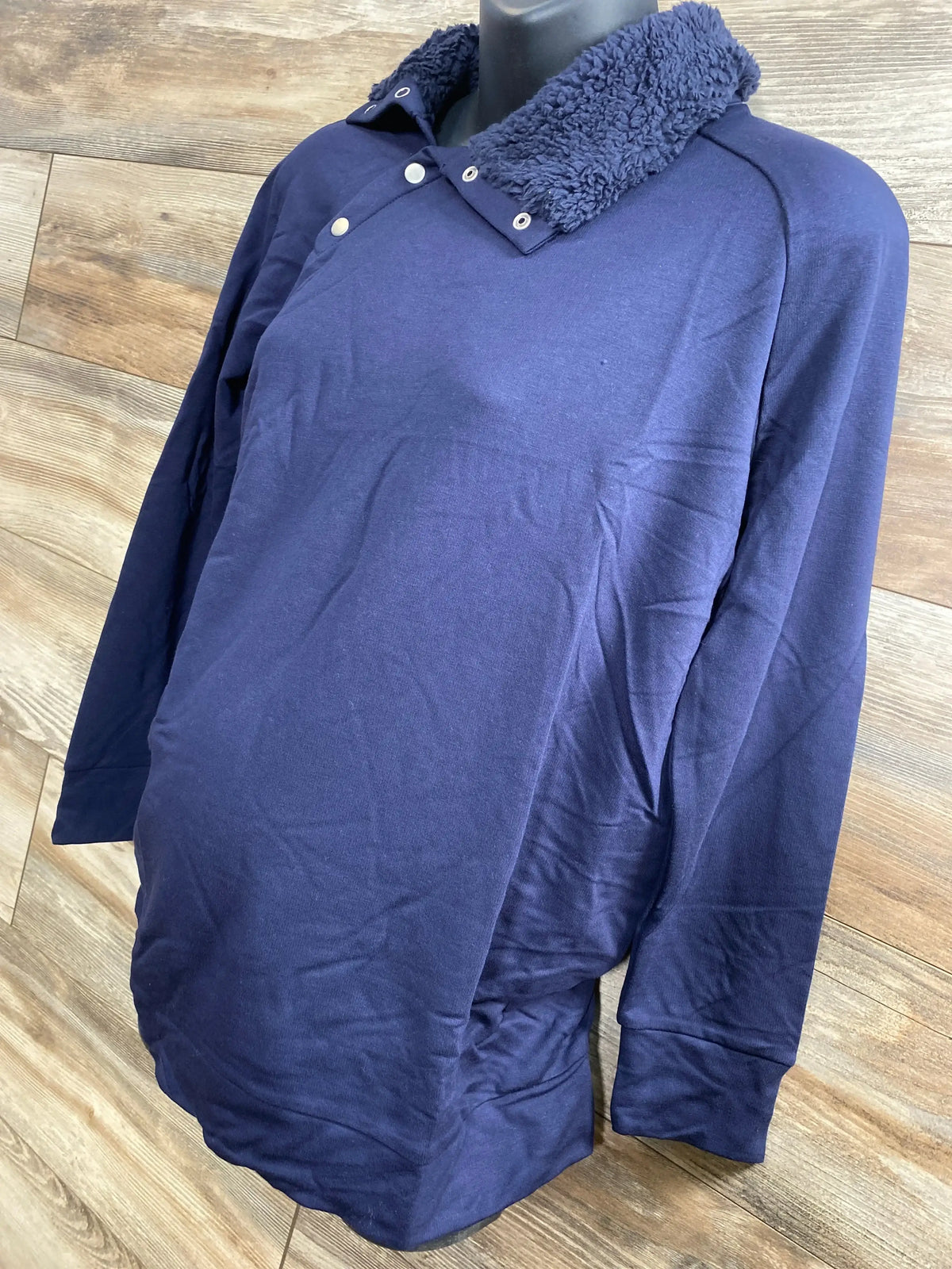 Front three-quarter of navy Isabel maternity sweatshirt with snap sherpa collar on mannequin, wood backdrop