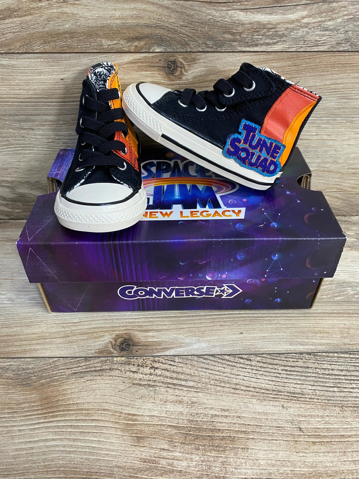 Angled front view of Chuck Taylor 70 Hi Converse sneakers size 5C with Tune Squad patch and orange heel on Space Jam box