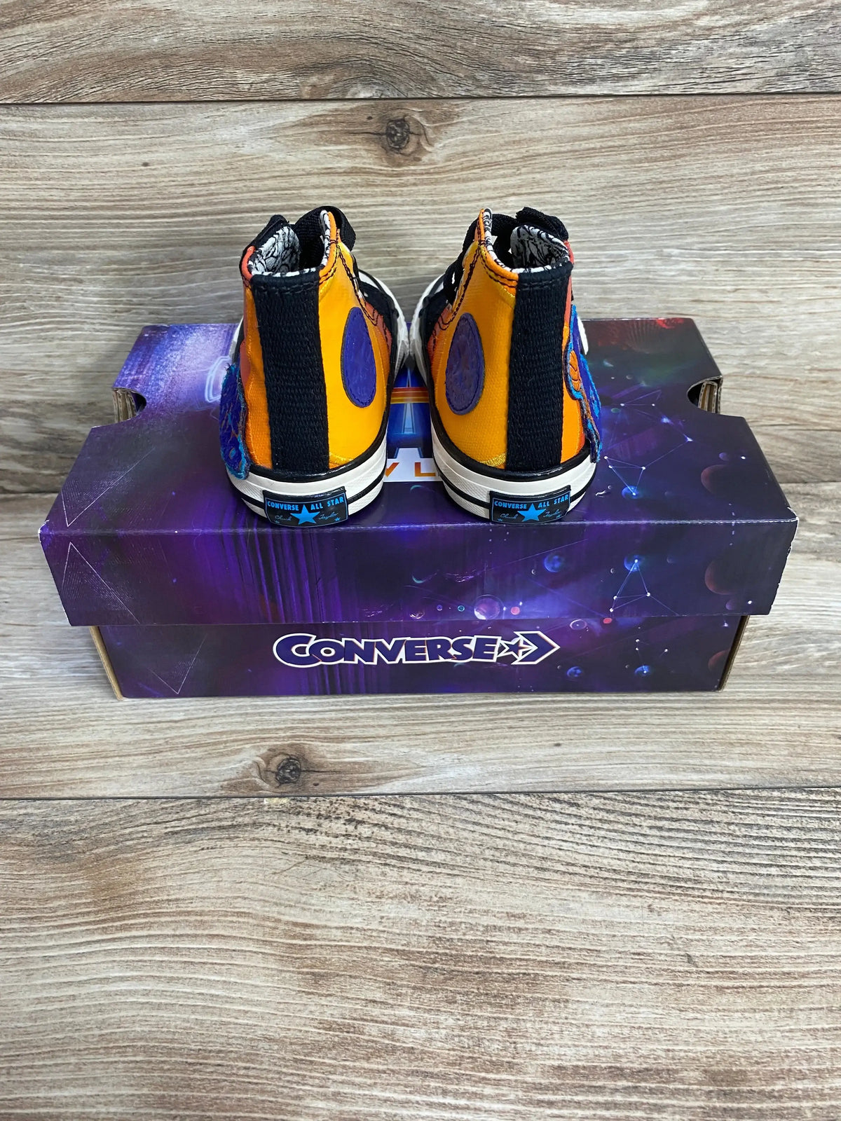 Rear view of Converse Chuck Taylor 70 Hi Space Jam toddler high-top sneakers with orange multicolor panels on a purple box
