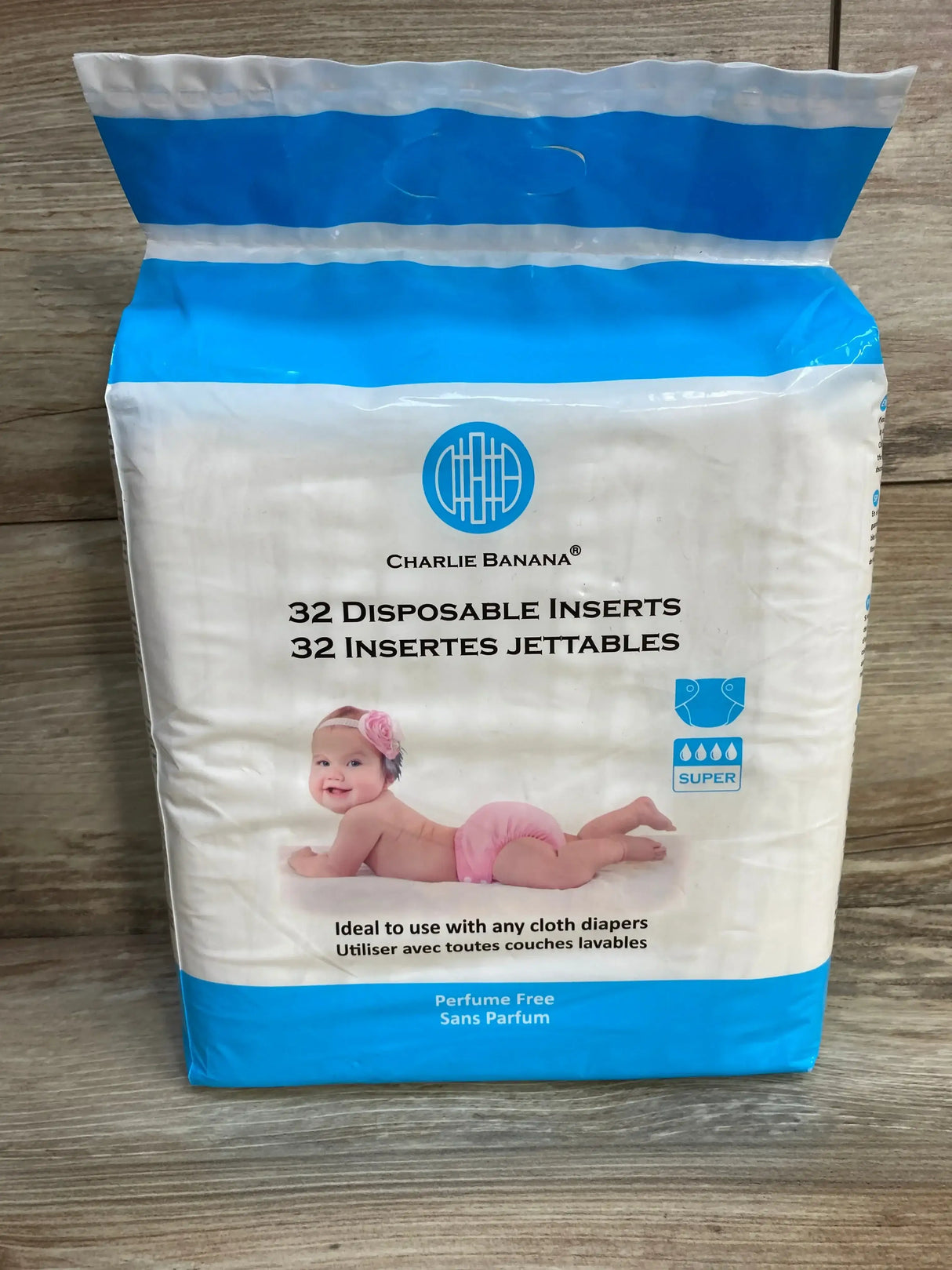 Front view of Charlie Banana disposable cotton diaper inserts, 32 count, with baby image and Perfume Free label on wood surface