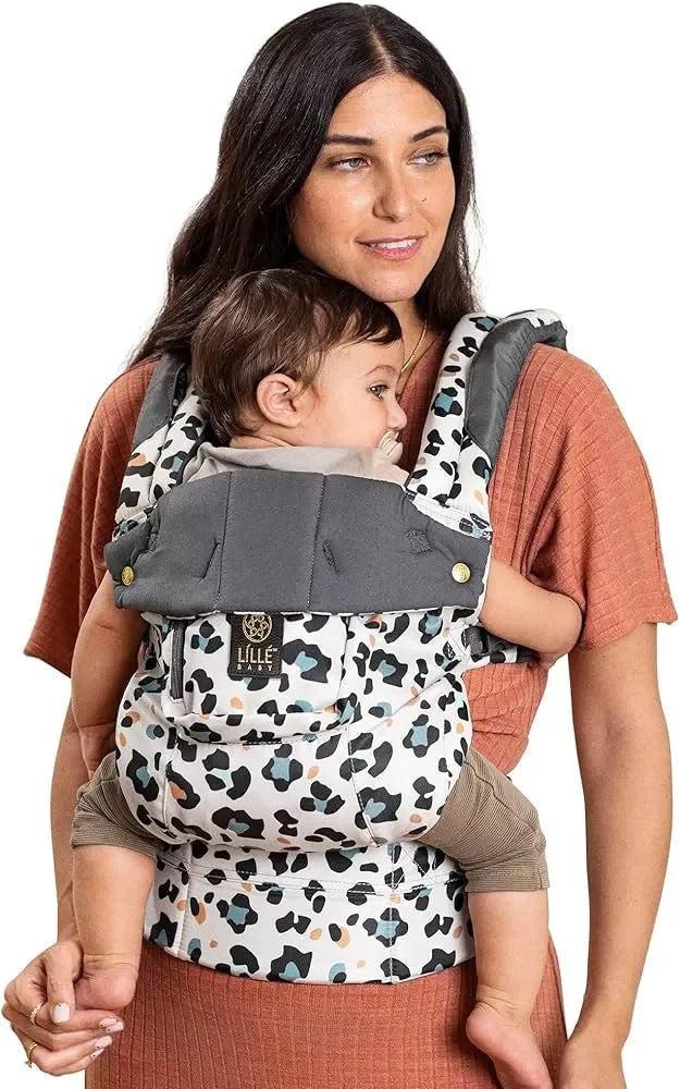 Woman wearing rust-colored dress carrying baby in gray and patterned Lille Baby carrier, close-up