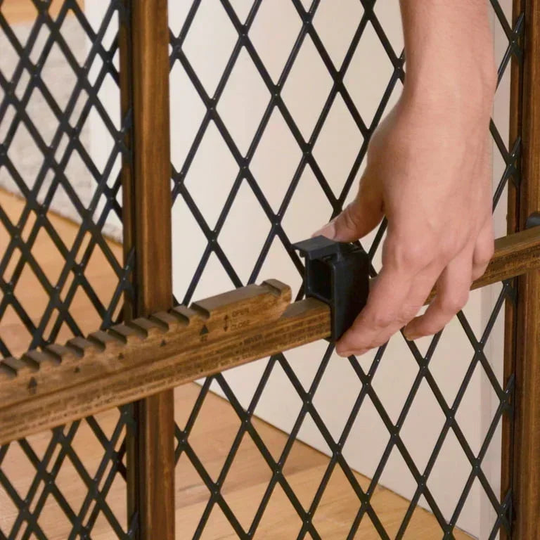 Close-up of Evenflo Position & Lock doorway gate showing wooden adjustable rail and black latch with hand on latch