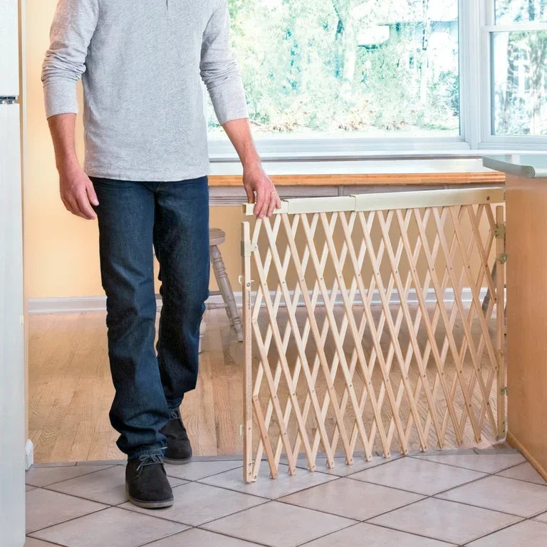 Wooden expandable baby safety gate installed in a bright kitchen doorway