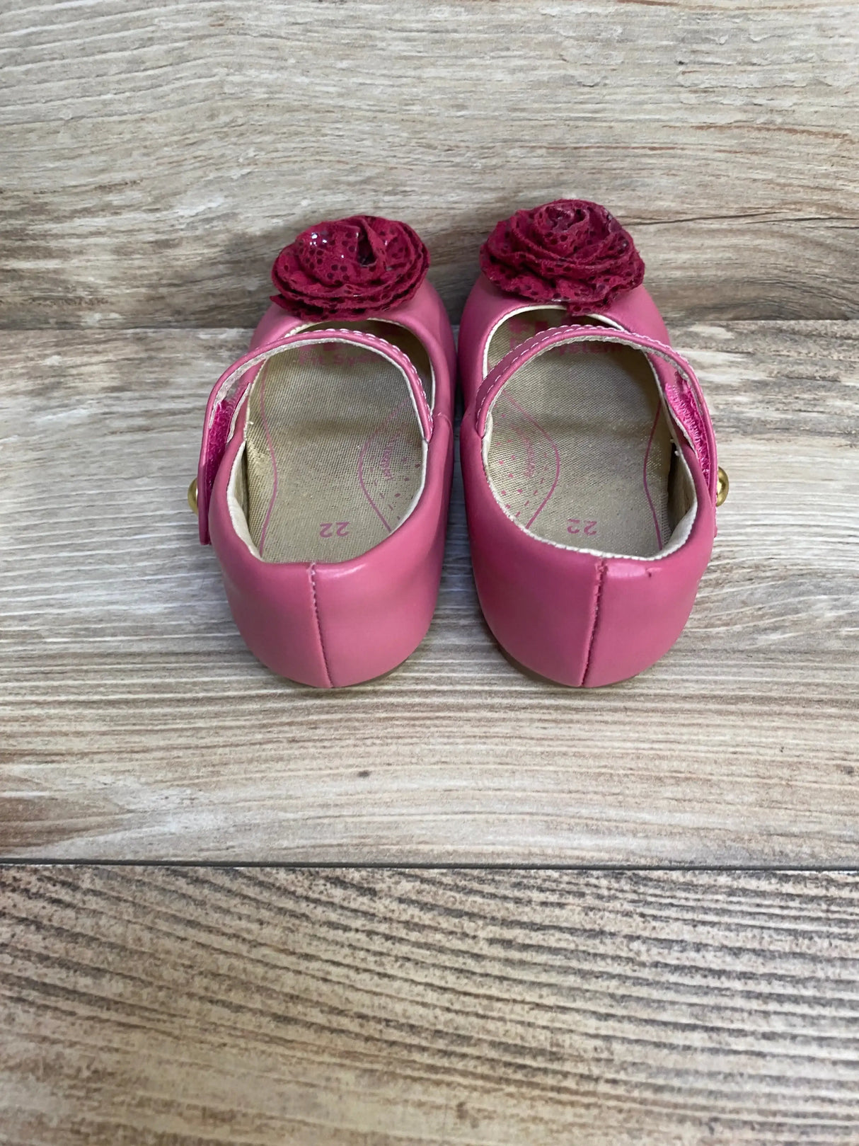 Rear view of Pediped Mary Jane pink toddler shoes showing lace rosettes, Mary Jane straps, and insole size 22 on wood floor