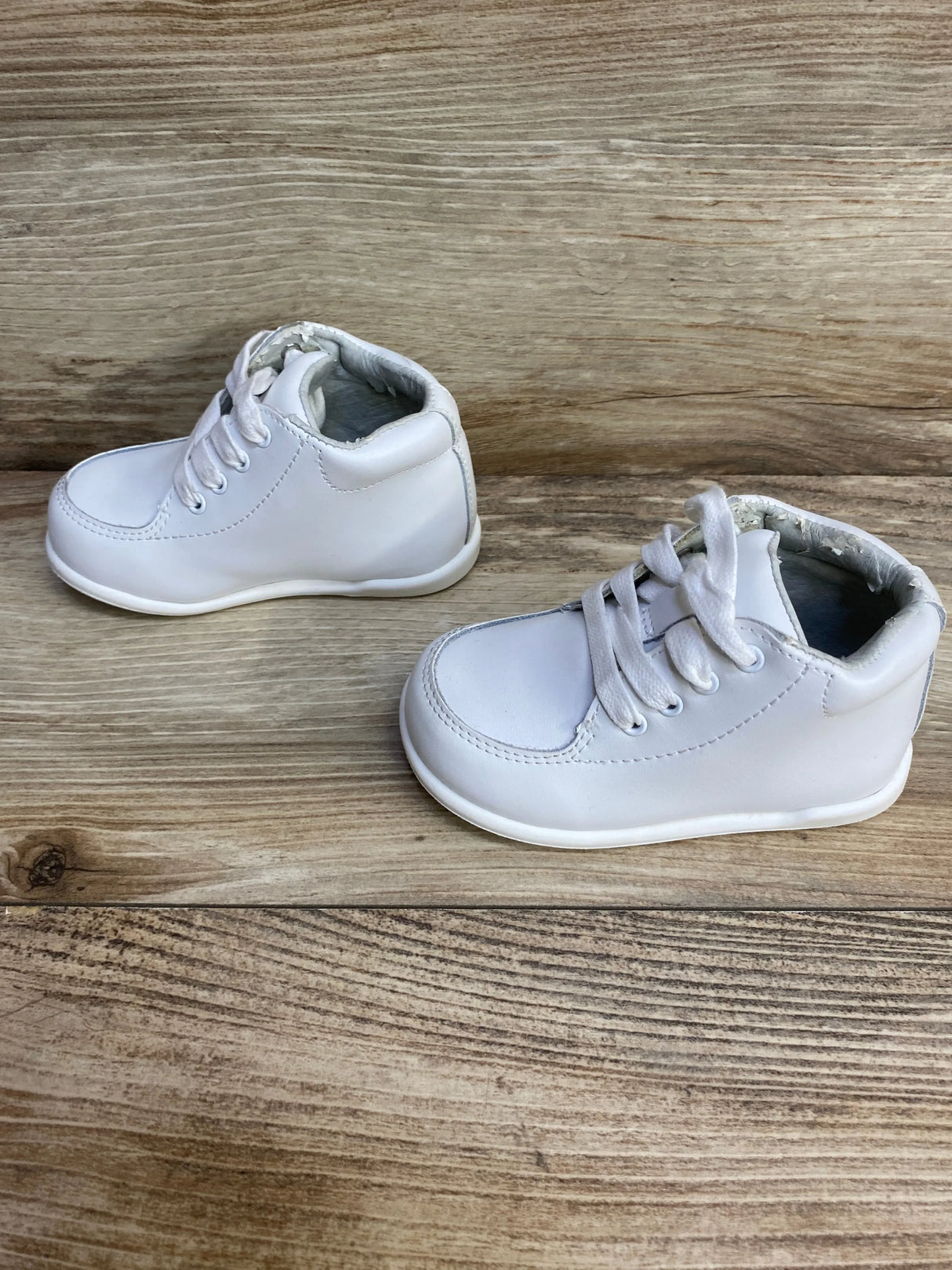 Front-right view of white Smart Step baby walking shoes showcasing lace-up closure and padded ankle on wood background