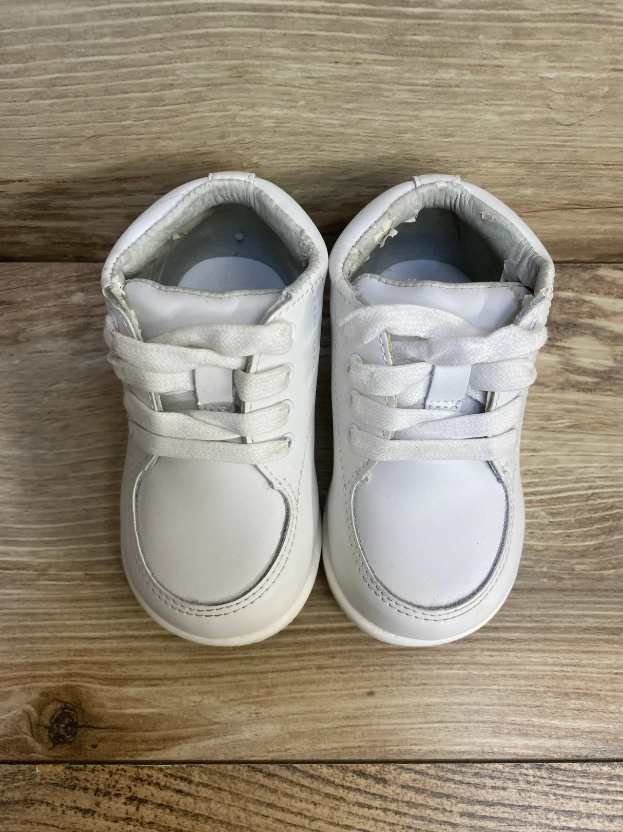Top view of Smart Step white toddler walking shoes size 5C showing laces and worn inner lining on wood plank background