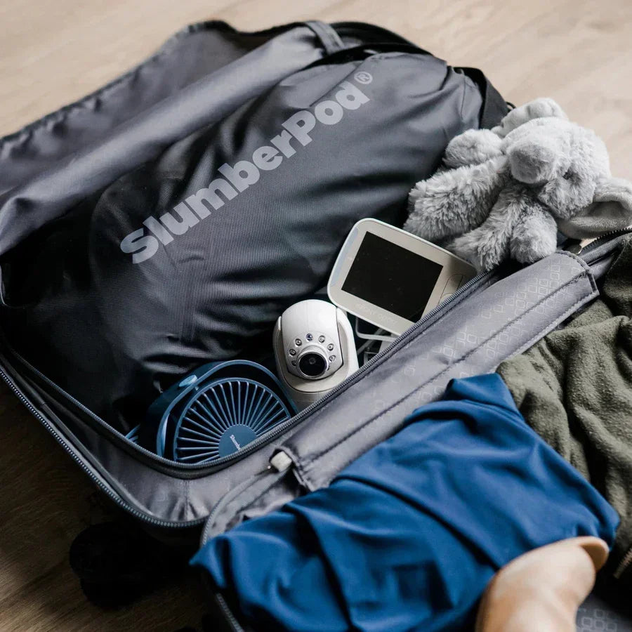SlumberPod travel bag packed with baby monitor, fan, stuffed toy, and clothes for easy travel