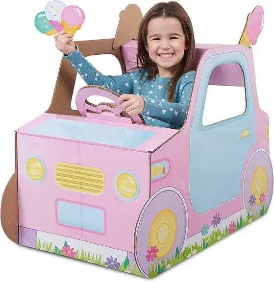 Three-quarter view of the pink Pop2Play cardboard car showcasing its steering wheel and floral design with a child seated inside