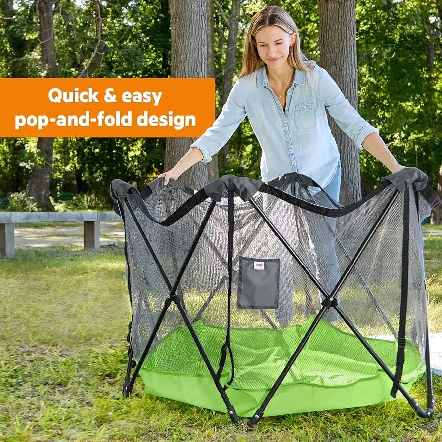 Green Bright Starts Pop N Play indoor outdoor playard showing its quick and easy pop and fold design with woman outdoors