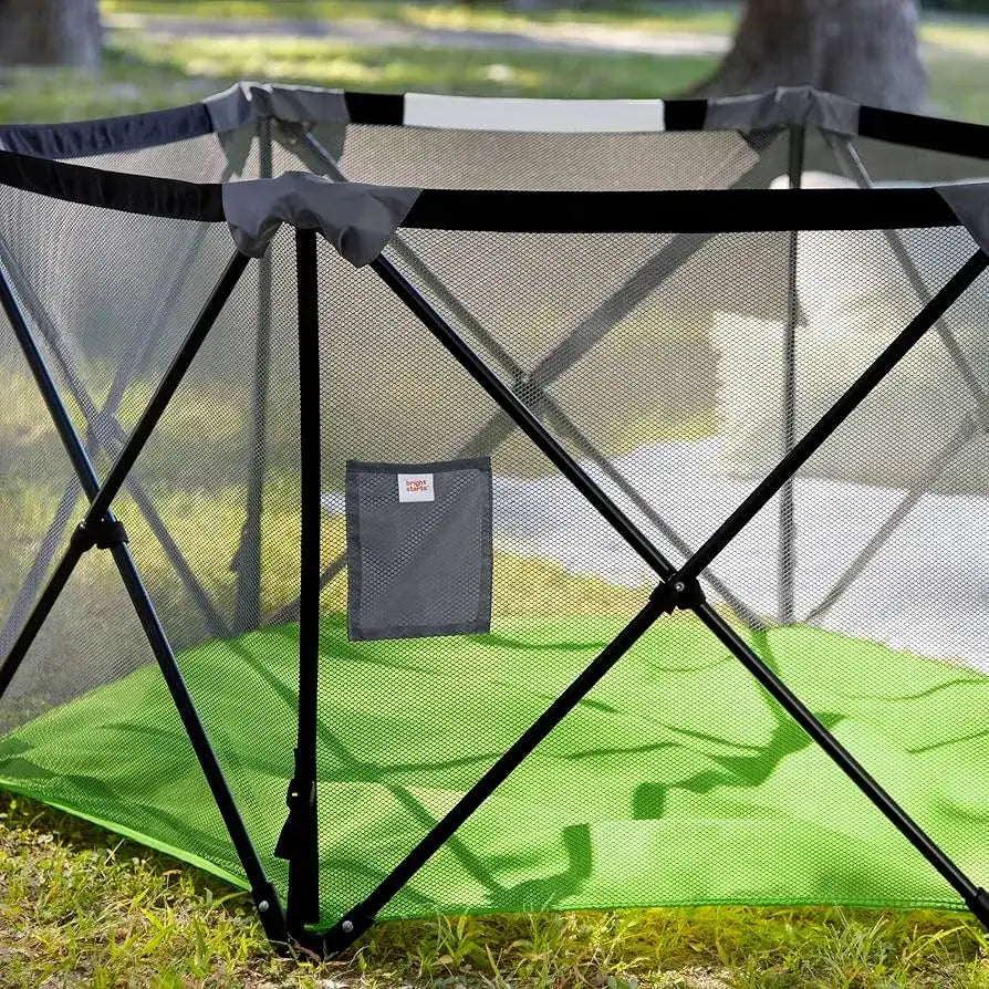 Bright Starts Pop 'N Play Indoor/Outdoor Playard with green mat and mesh siding on grass