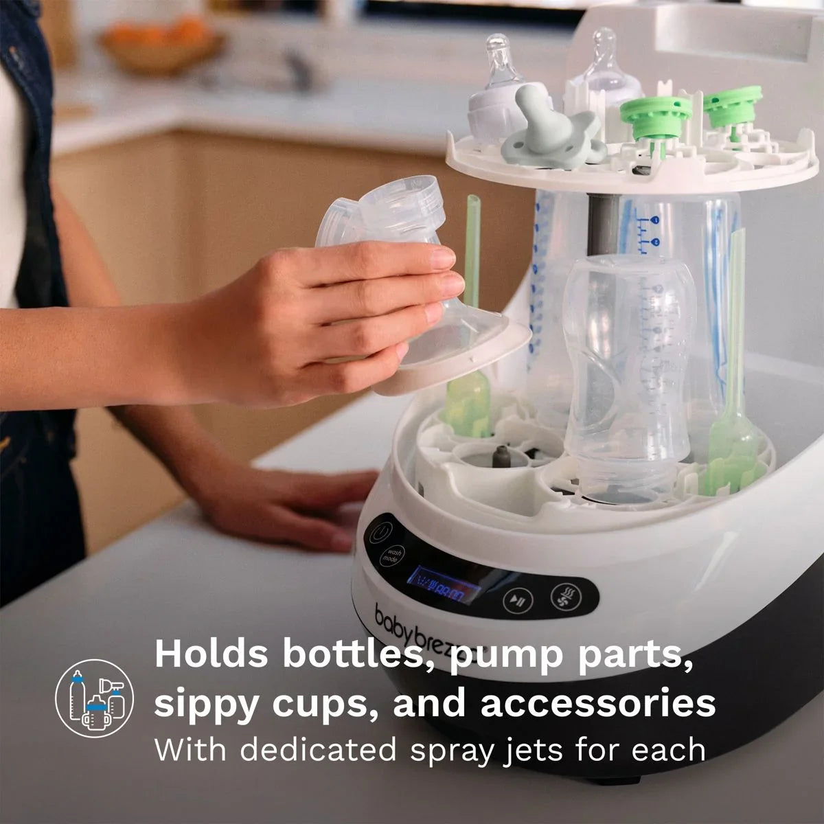 Front view of Baby Brezza Bottle Washer Pro showing bottle and pump-part holders and dedicated spray jets on counter