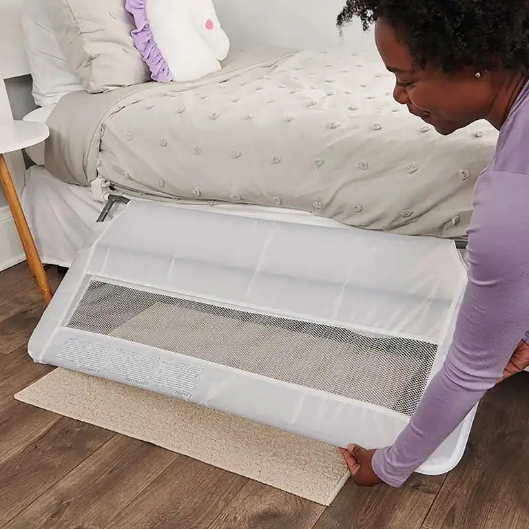 Angled view of white Regalo Swing Down Bed Rail Guard showcasing its mesh panel and frame beside a bed