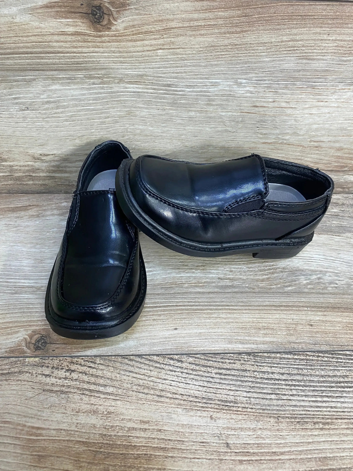 Two black Deer Stags Brian slip on kids dress shoes, size 9C, shiny upper on wood background