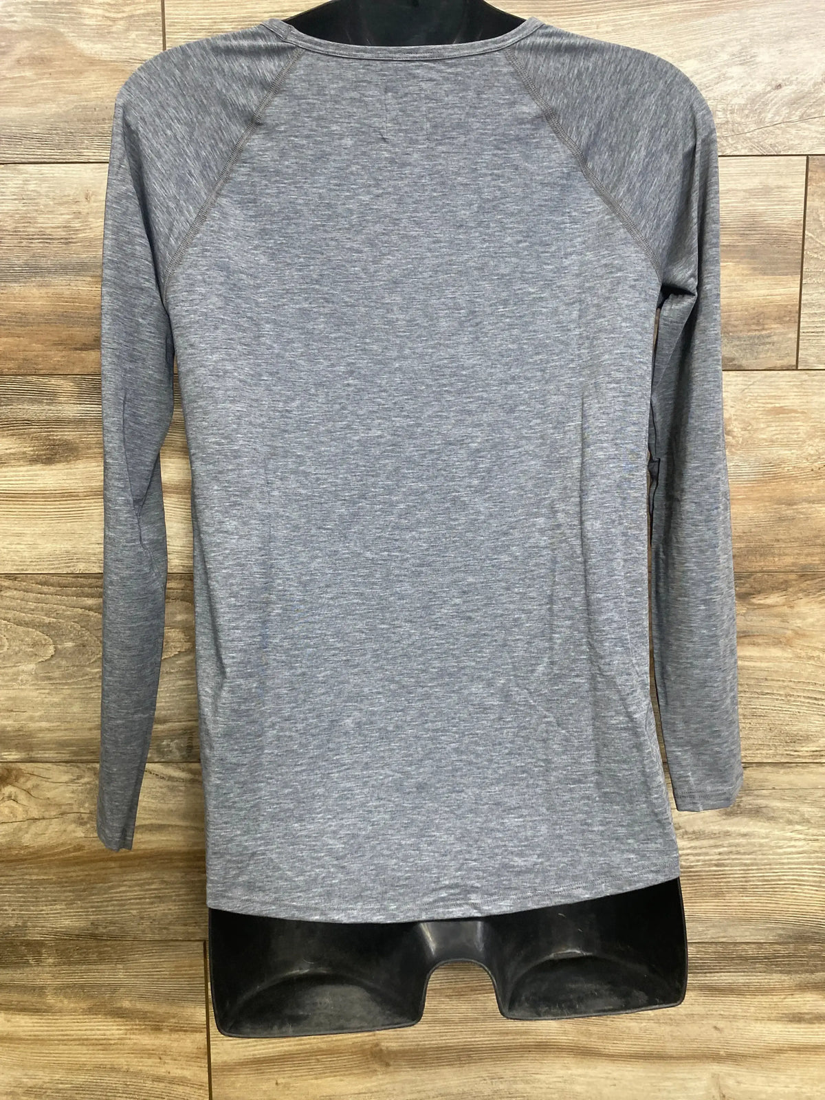 Back view of Gap Breathe maternity long-sleeve shirt in heather gray showing raglan sleeves on black mannequin over wood wall