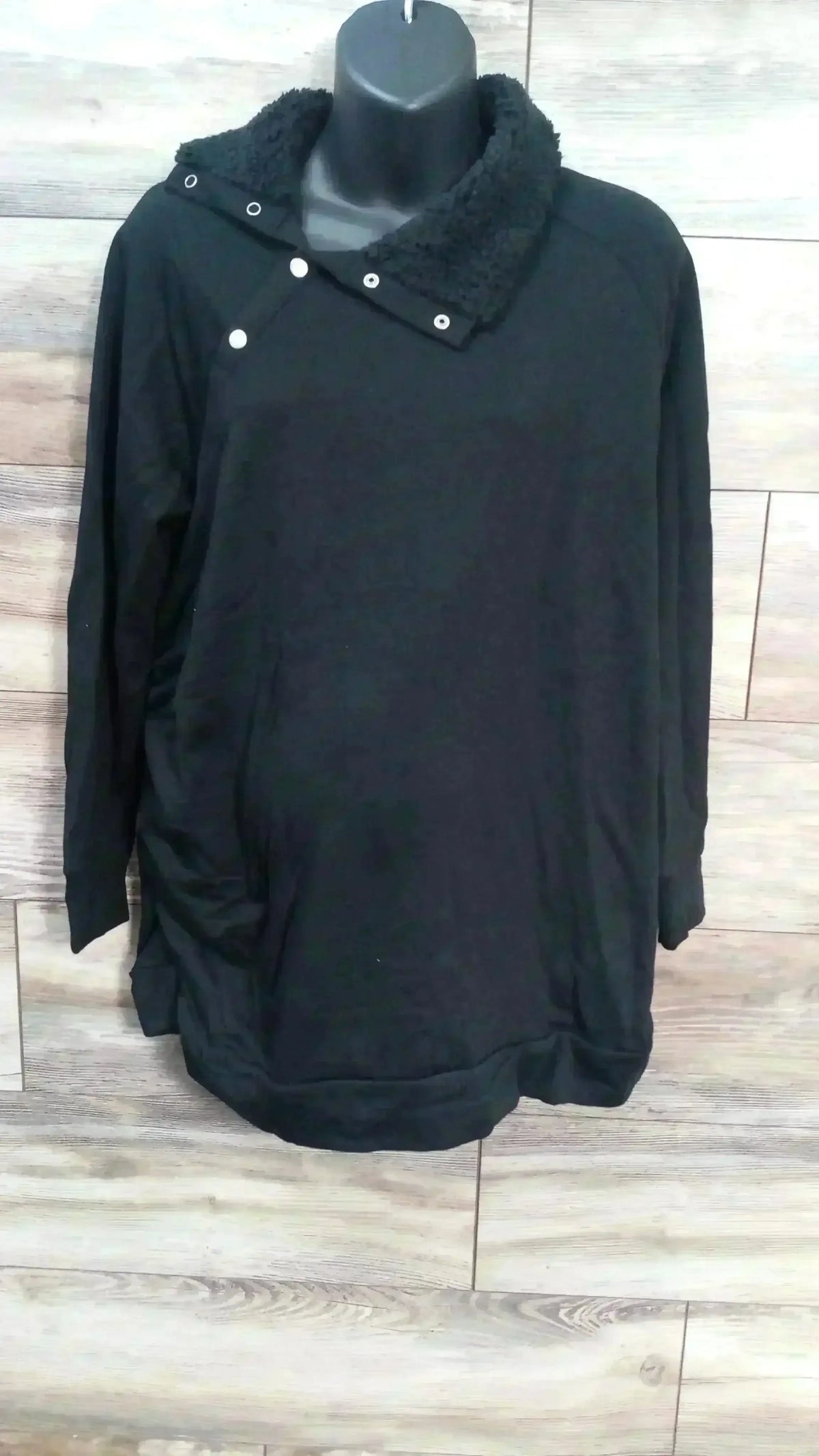 Front view of black maternity sweatshirt showcasing sherpa snap collar, kangaroo pocket and relaxed oversized fit on wood plank background