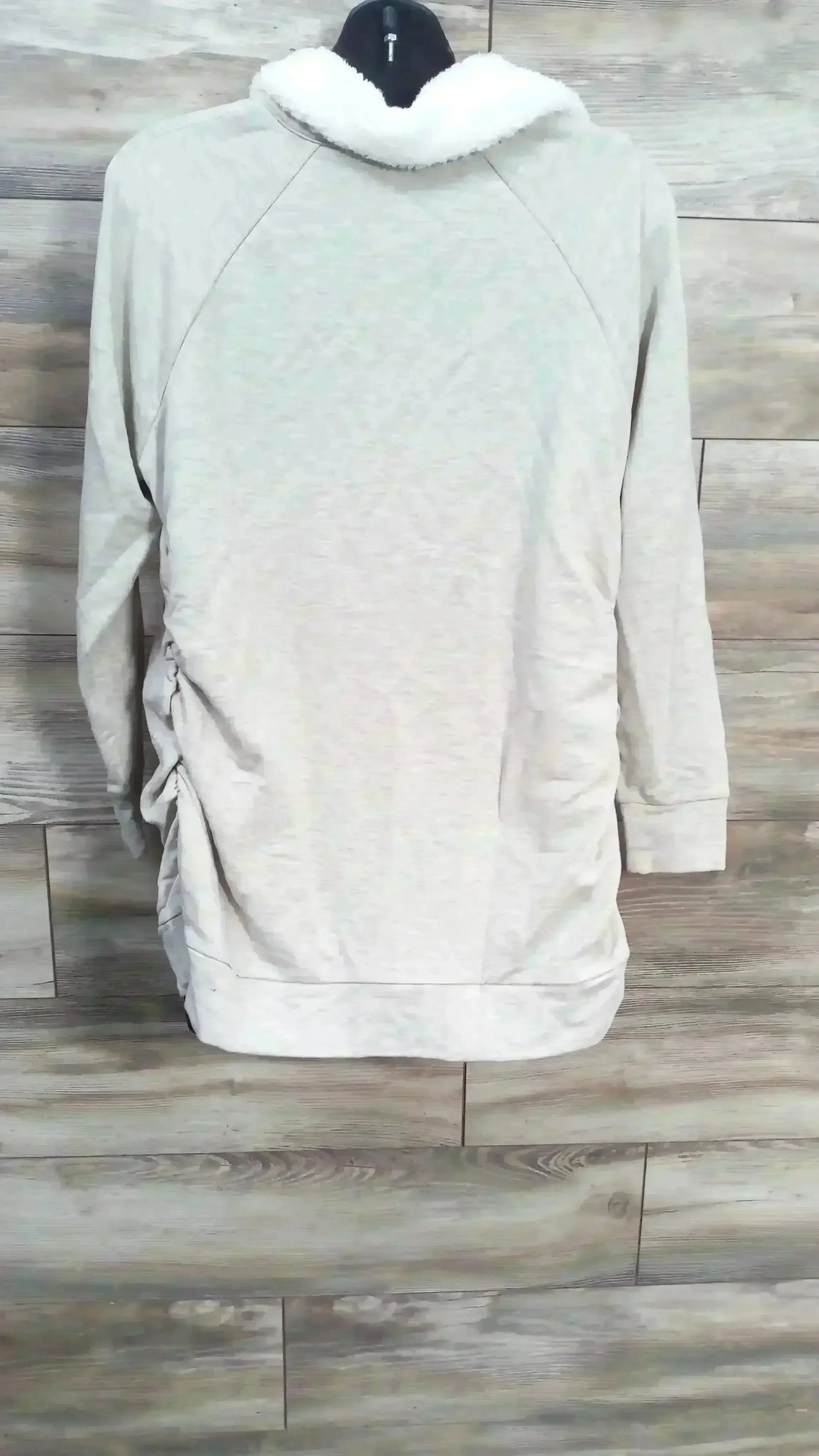 Back view of oatmeal Isabel maternity sweatshirt showcasing sherpa-lined snap collar and side ruching on wood-plank background