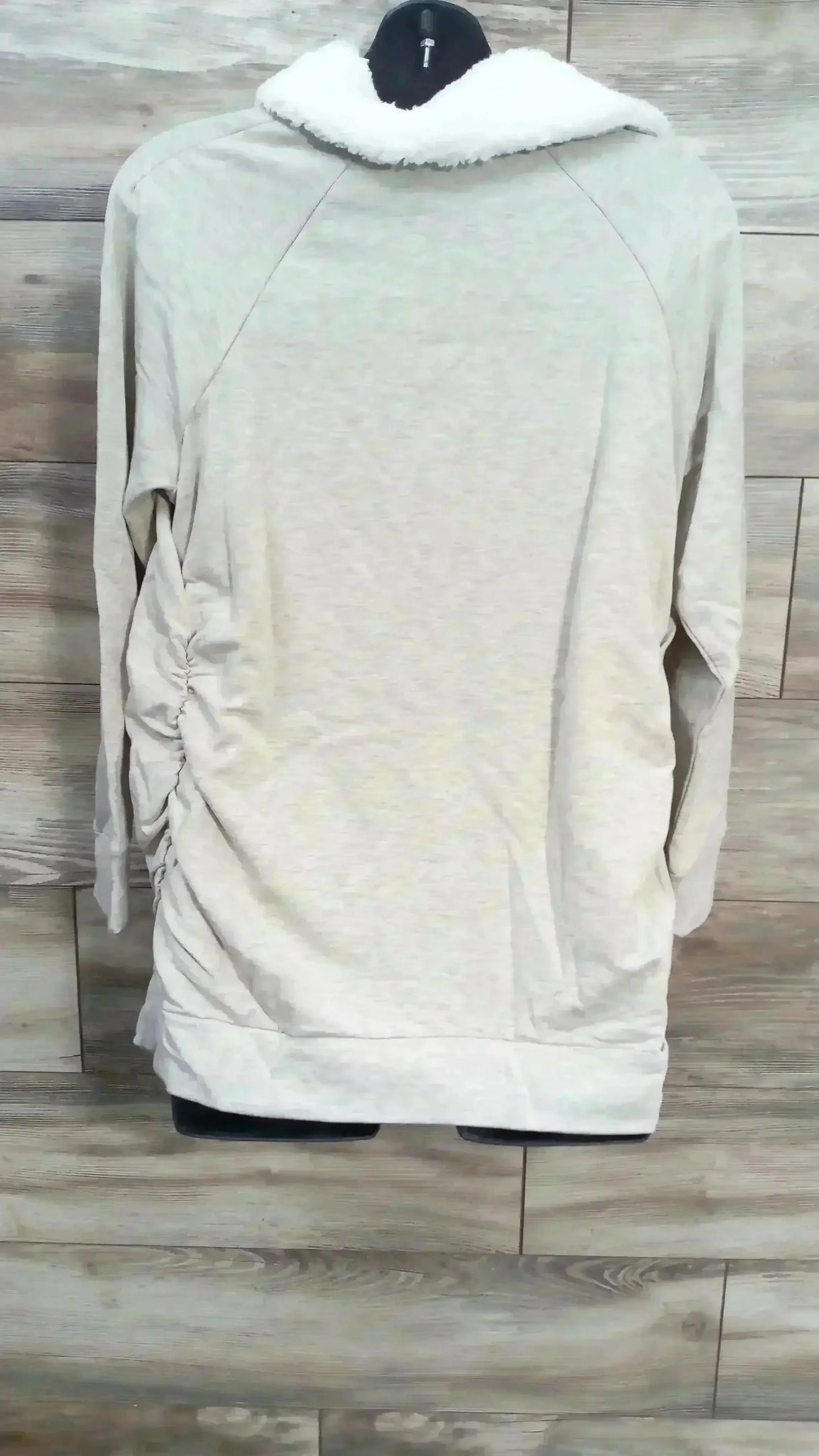 Back view of Isabel maternity oatmeal sweatshirt showcasing sherpa collar and side ruching on a wood plank backdrop