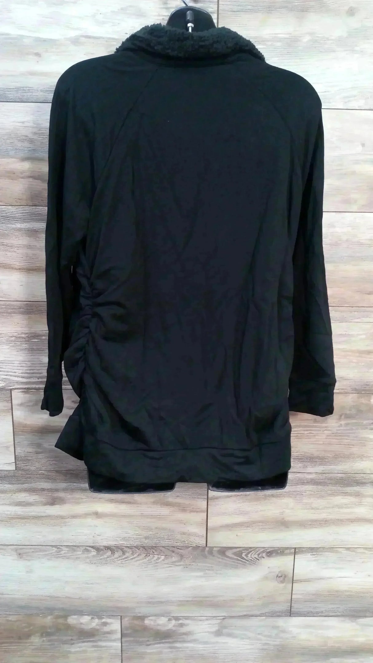 Back view of Isabel maternity sweatshirt showing sherpa-lined collar and side ruching on light wood plank background