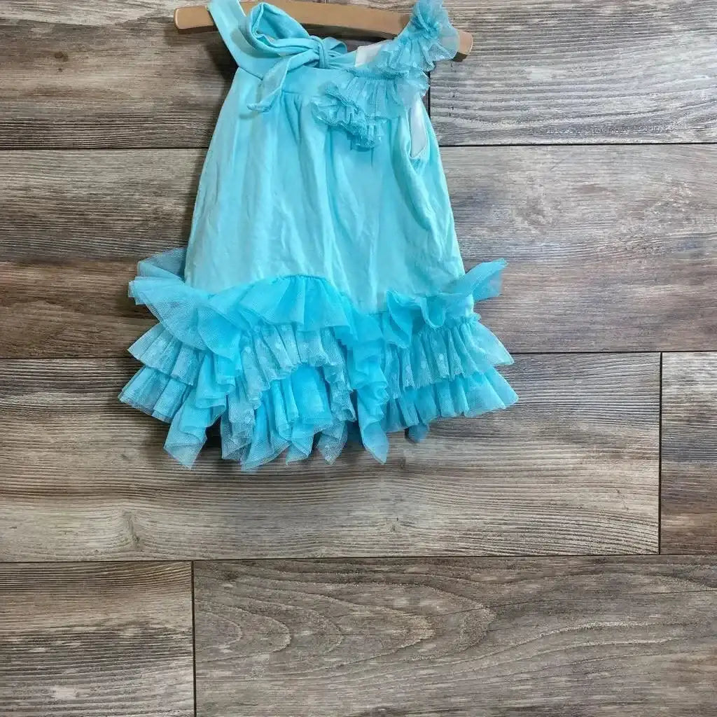 Front view of Isobella and Chloe turquoise ruffle tunic with bow neckline and tiered tulle hem on wood hanger on wood plank floor