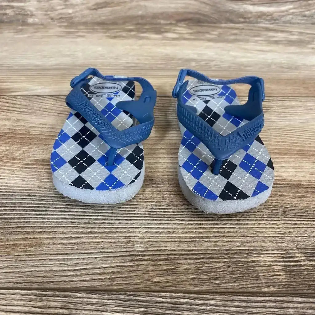 Front view of Havaianas flip flops size 8C with blue, gray, and black argyle pattern and elastic back straps on wood