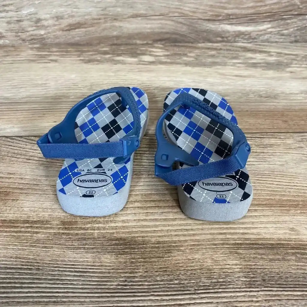 Front view of Havaianas flip flops showcasing blue elastic back straps and plaid footbeds on a wood floor