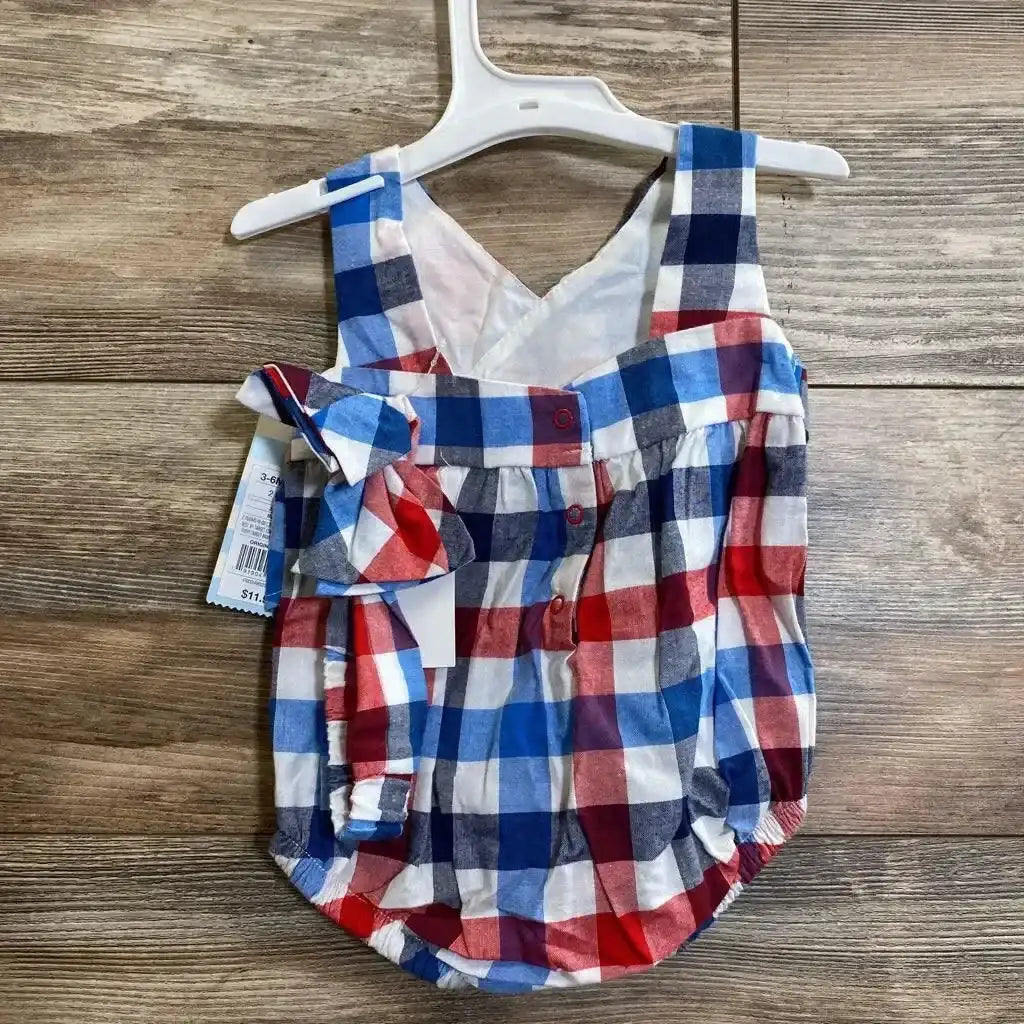 Front view of baby plaid romper (3–6 months) with red, blue and white checks, side bow and front buttons on hanger over wood floor