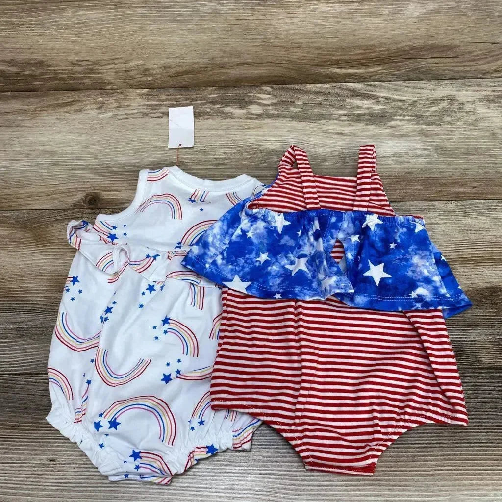 Flat lay of two Cat and Jack baby rompers, white rainbow-print and red-striped with blue star ruffle, size 0-3M on wood
