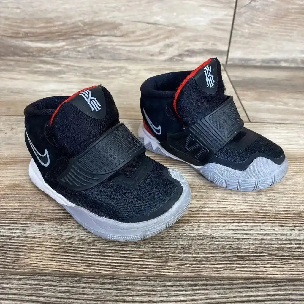 Three-quarter view of black Nike Kyrie 6 toddler sneakers size 4C with Velcro strap, white Swoosh and gray sole on wood floor