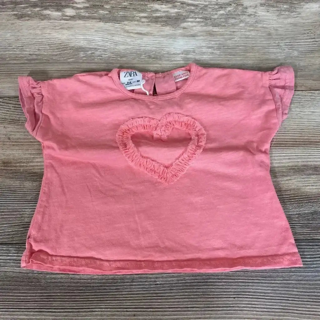 Flat lay of pink Zara baby shirt size 3-6 months showing ruffled heart applique, flutter sleeves, and back keyhole on wood background