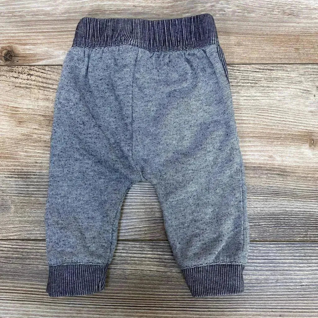 Flat lay of grey Cat & Jack newborn pants showing ribbed elastic waistband and navy cuffed ankles on wood background