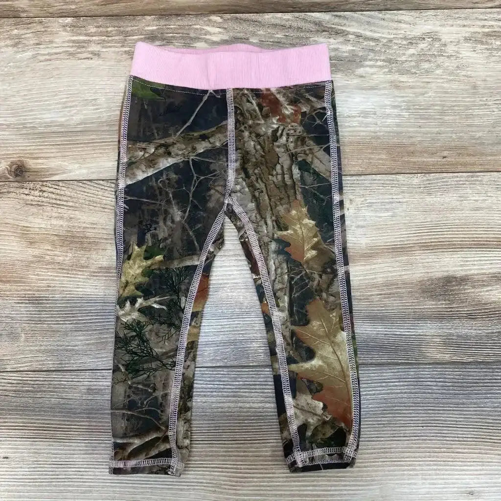 Flat-lay of kids' camo leggings size 2T with pink elastic waistband and ankle cuffs on wood background