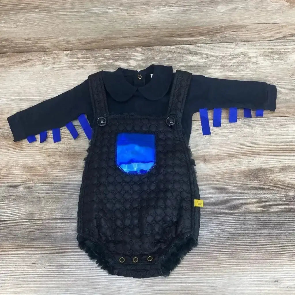 Flat lay of Chua bodysuit and faux-fur romper showcasing quilted texture, shiny blue front pocket and blue ribbon sleeve fringe on light wood background