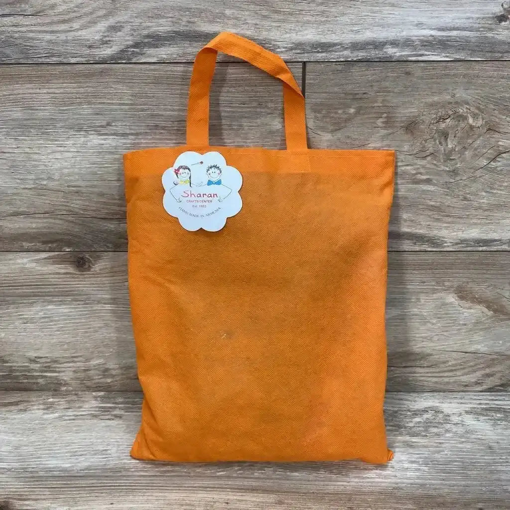 Front view of Sharan Crafts handmade red baby sweater dress (12M) packaged in orange tote with label on wood plank background