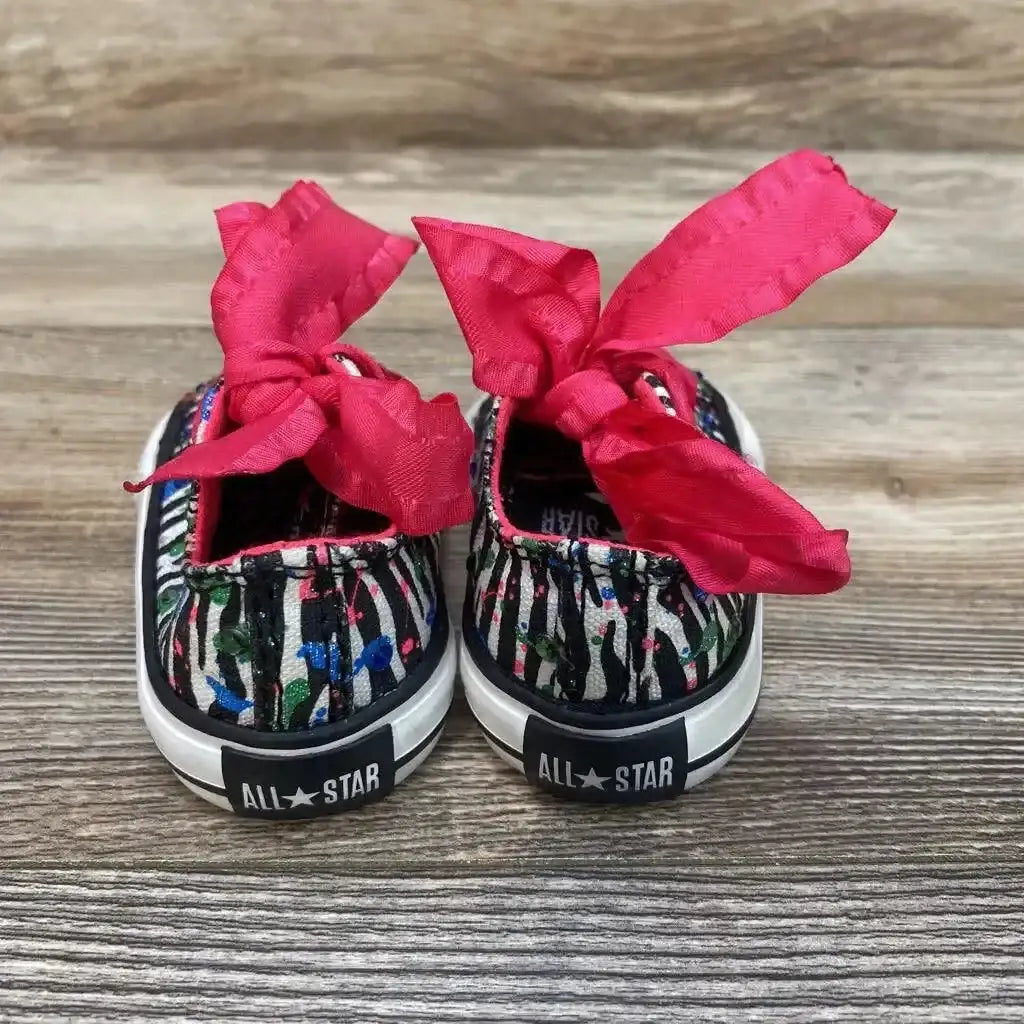 Rear view of toddler Converse low top sneakers with black and white glitter stripes and hot pink ribbon laces on wood floor
