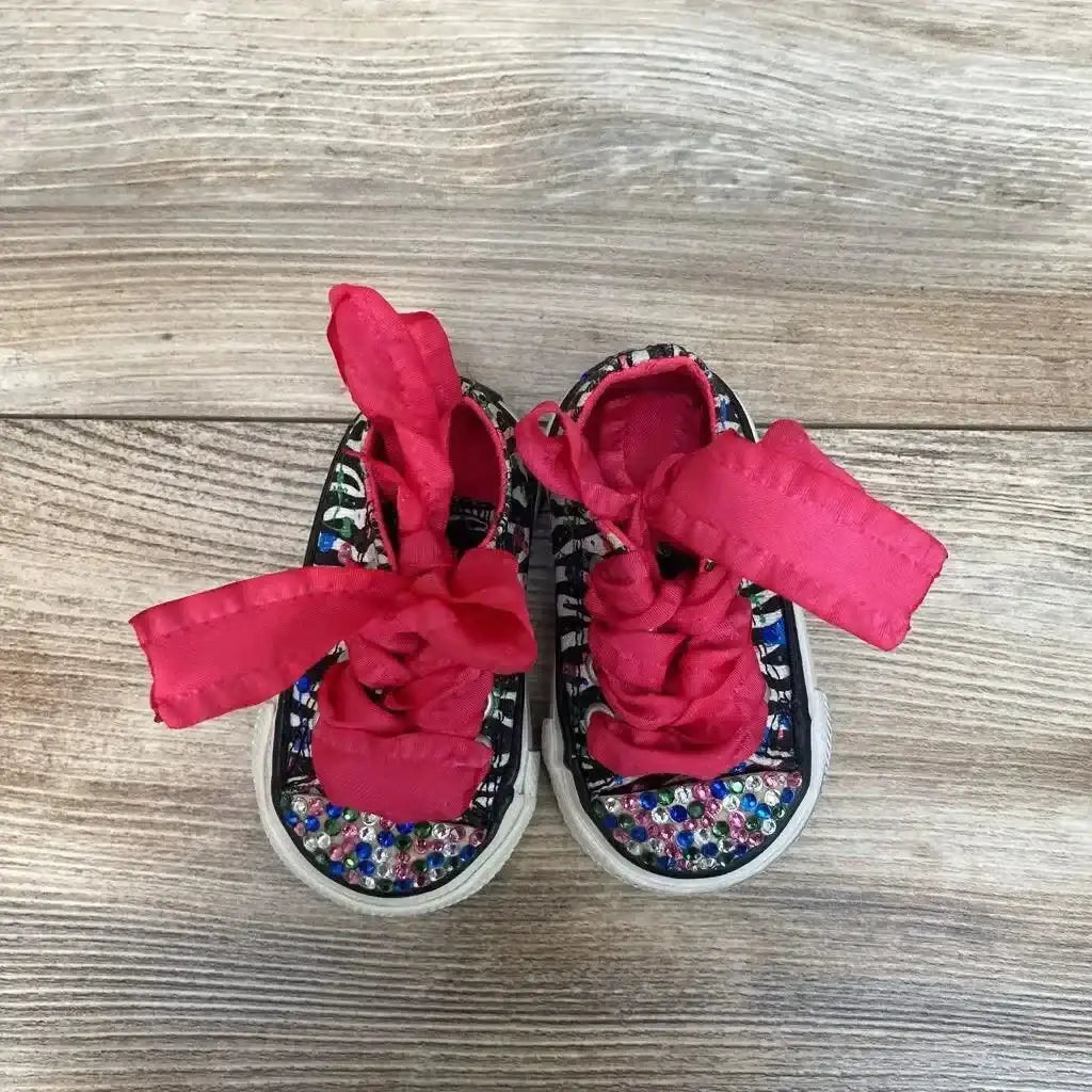 Angled view of used pink Converse Chuck Taylor low-top sneakers size 2C showing white toe and laces on plain background