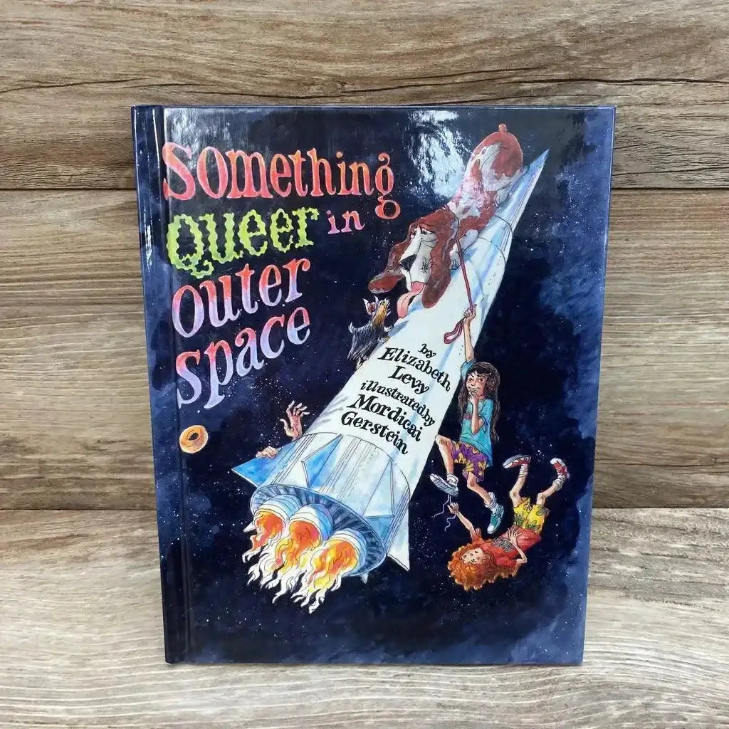 Front cover of Something Queer in Outer Space hardcover book by Elizabeth Levy with rocket and characters illustration on wood plank floor