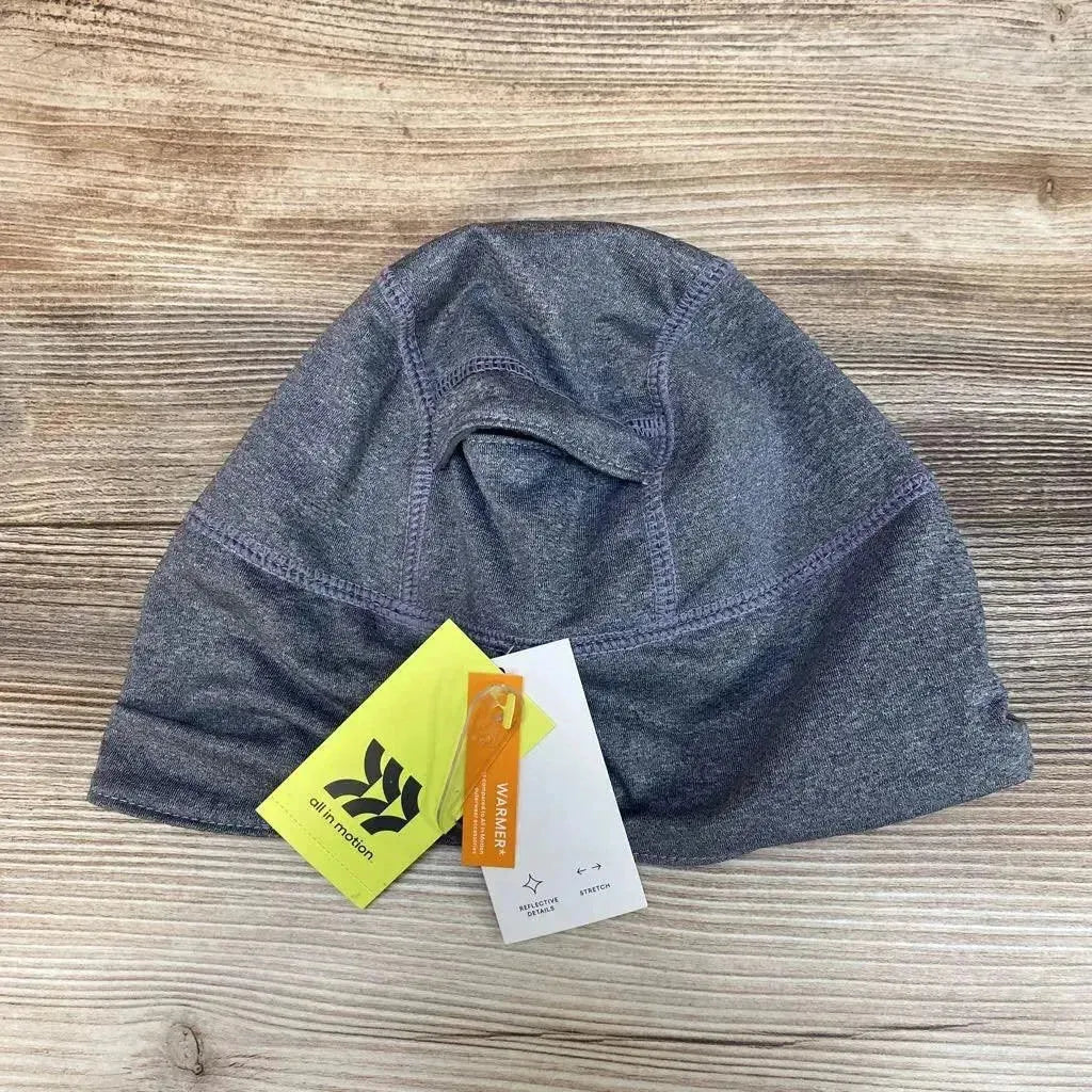 Top-down view of grey fleece-lined jersey beanie showcasing stitched seam details and attached tags on a wood background