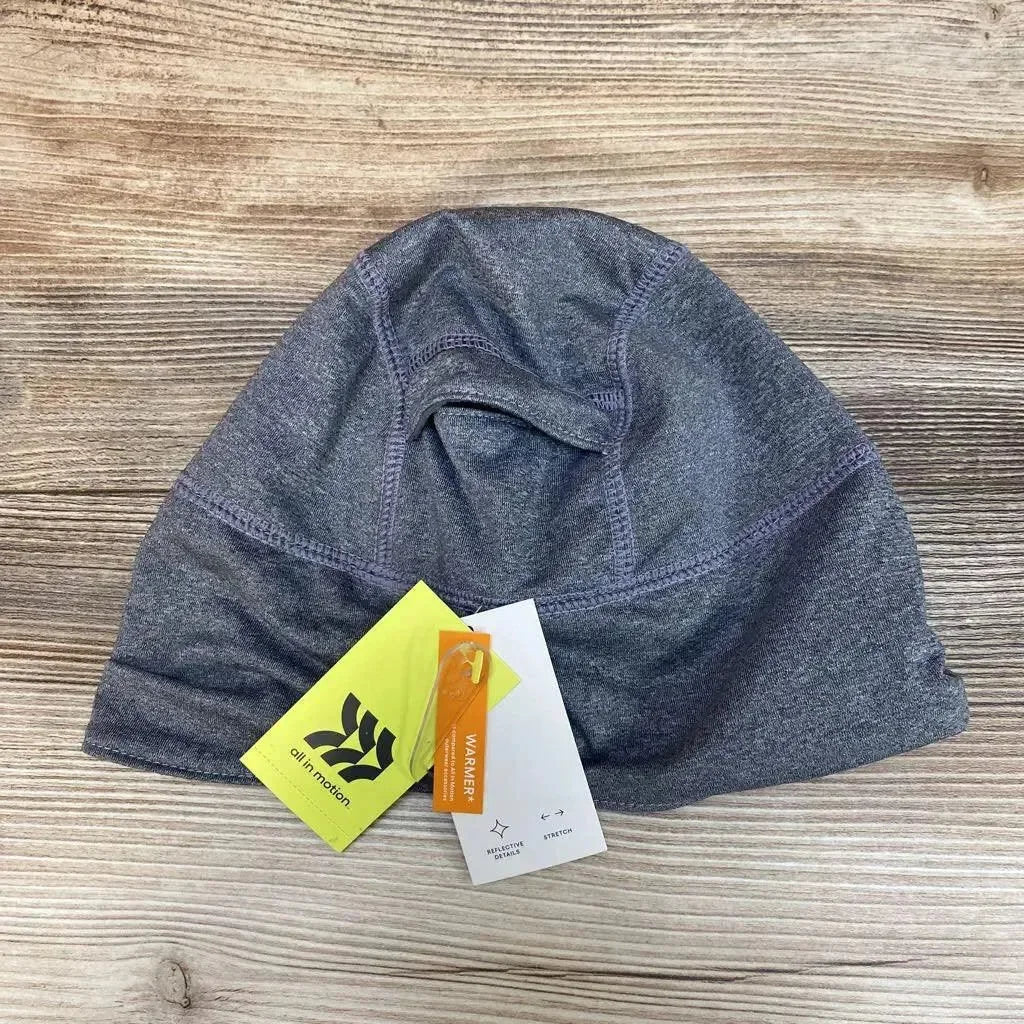 Top-down view of grey fleece-lined jersey beanie showcasing stitched seam details and attached tags on a wood background