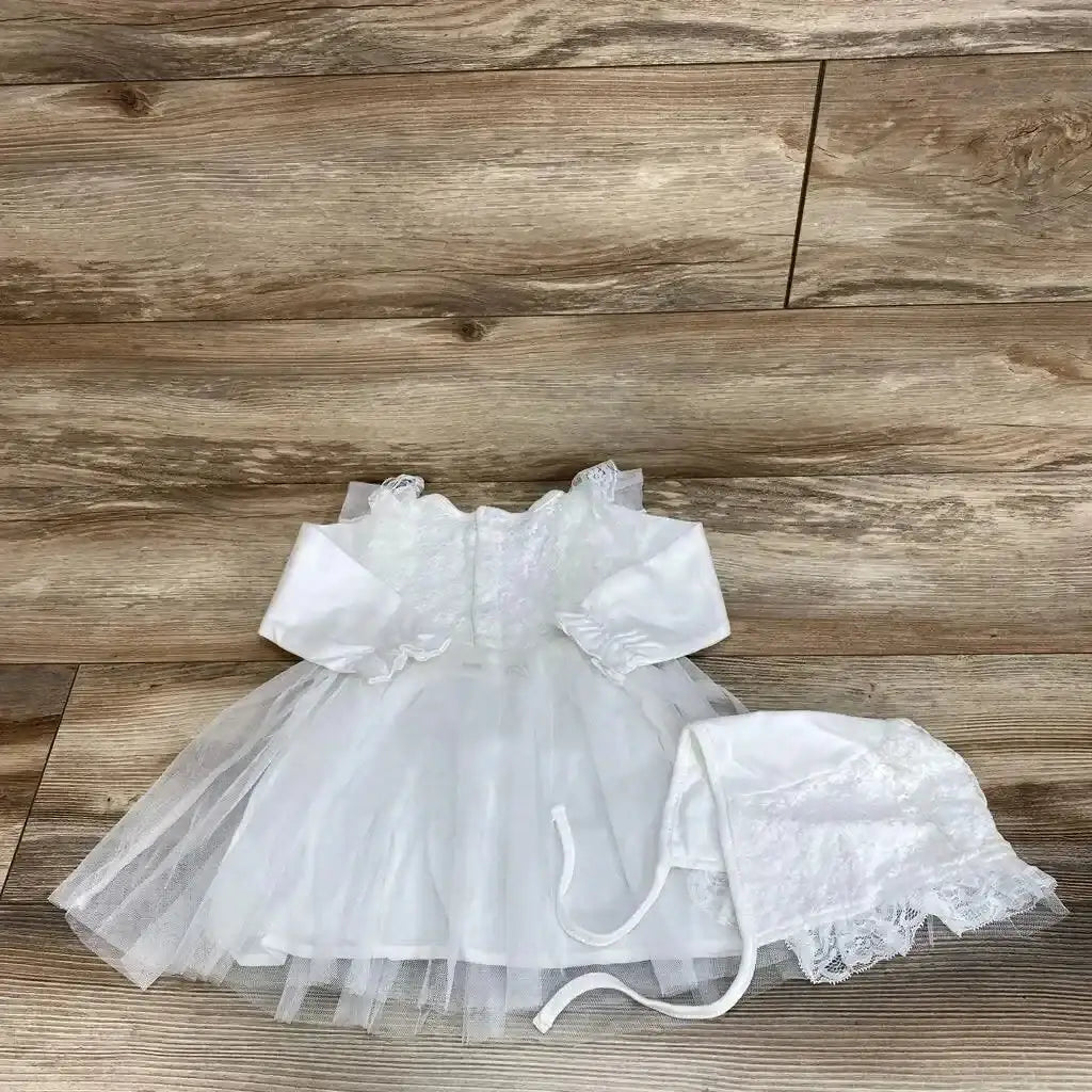 Overhead view of a tulle overlay dress and bonnet, size 6 to 9 months, with 100 percent cotton long sleeves on wood planks