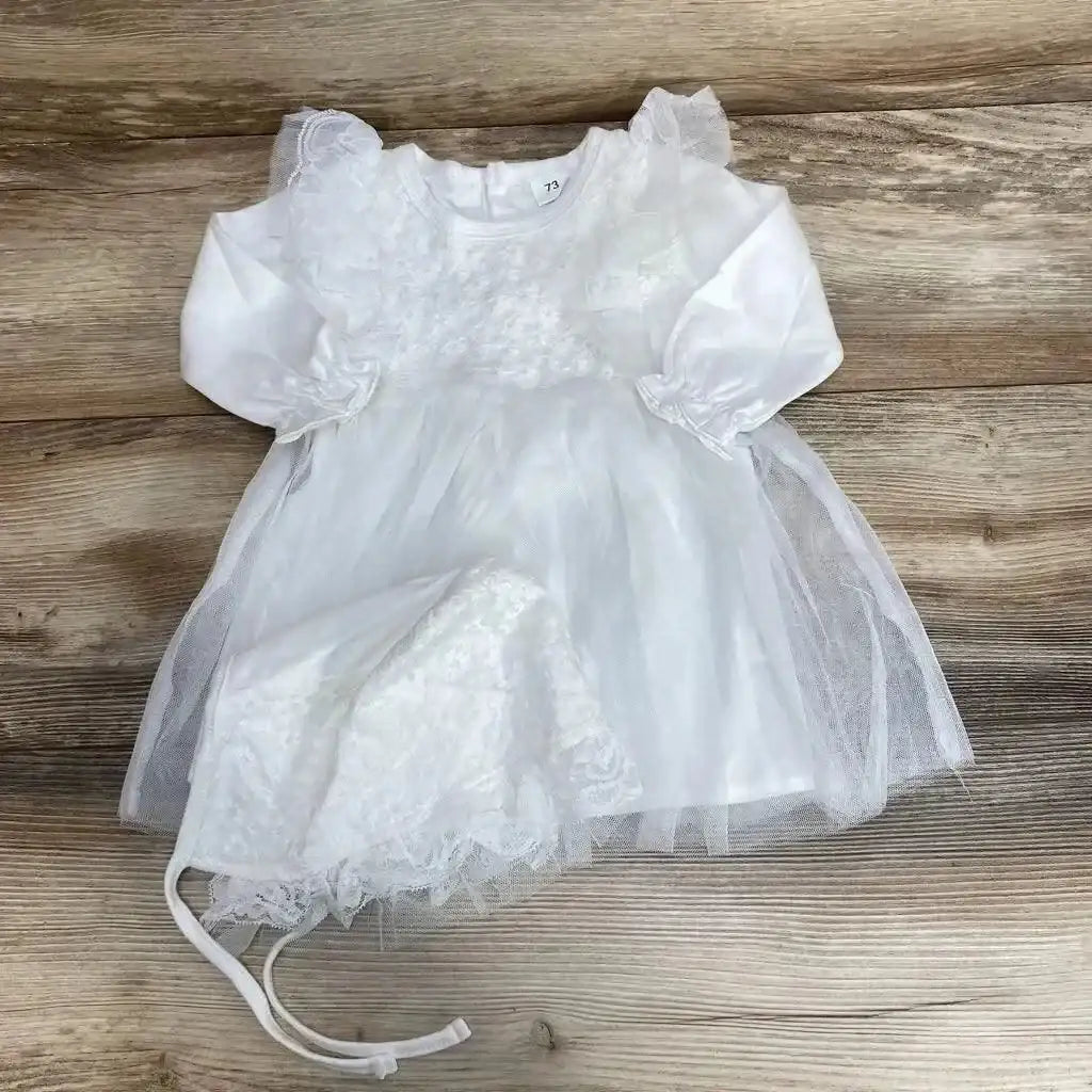 Flat lay of white baby dress size 6-9 months with tulle overlay, lace floral bodice and matching bonnet on wood background