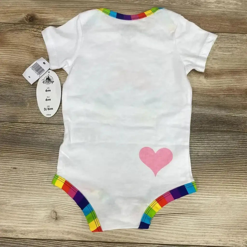 Flat lay back view of white Disney Parks baby bodysuit 6M showcasing rainbow trim and pink heart, Disney size tag on wood background