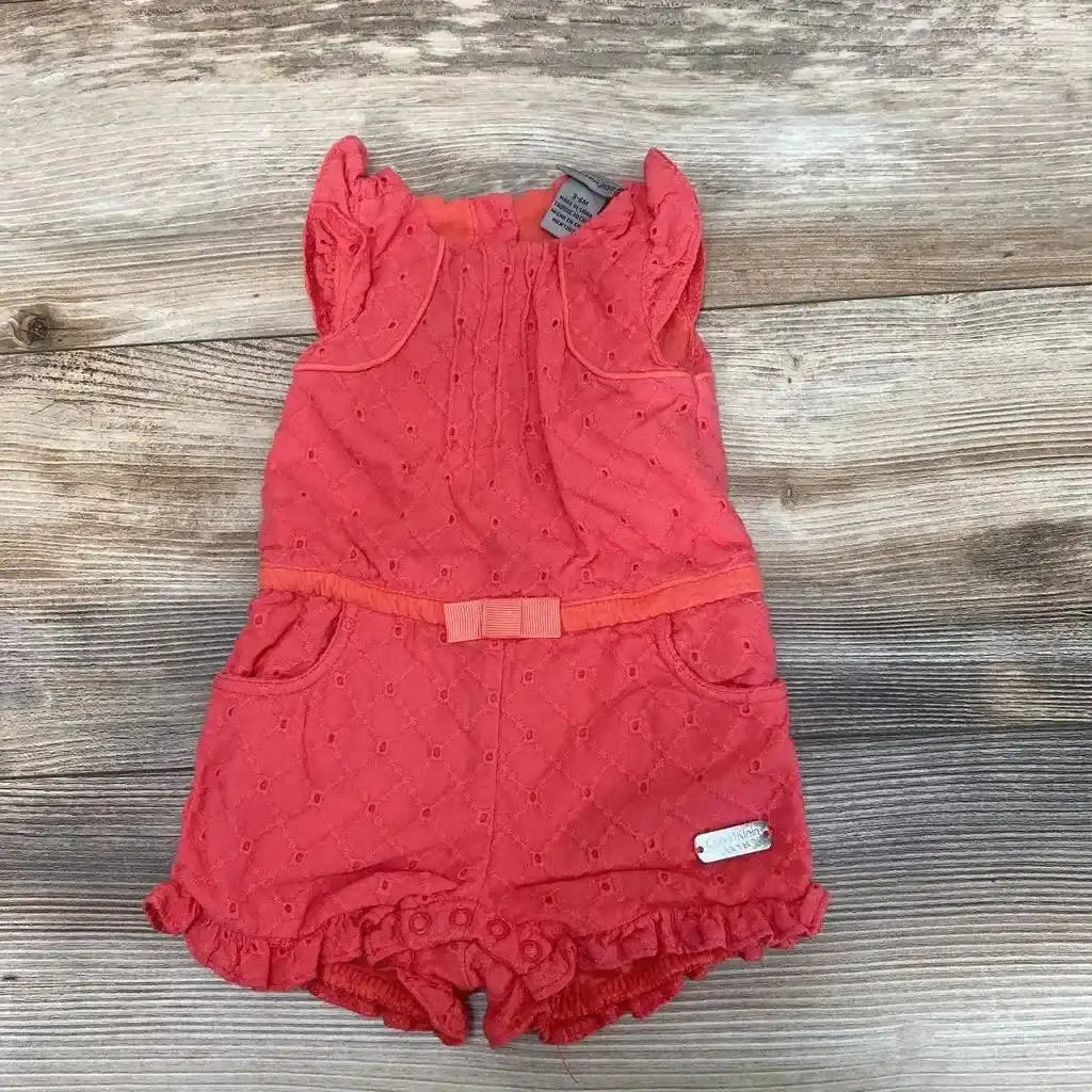 Front view of Calvin Klein Eyelet Romper sz 3-6m showcasing coral eyelet fabric, waist bow, pockets, and ruffled hem on wood