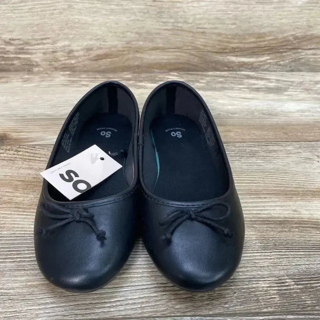 Top-down view of toddler black ballet flats showcasing front bow detail and attached NEW SO tag on wood floor