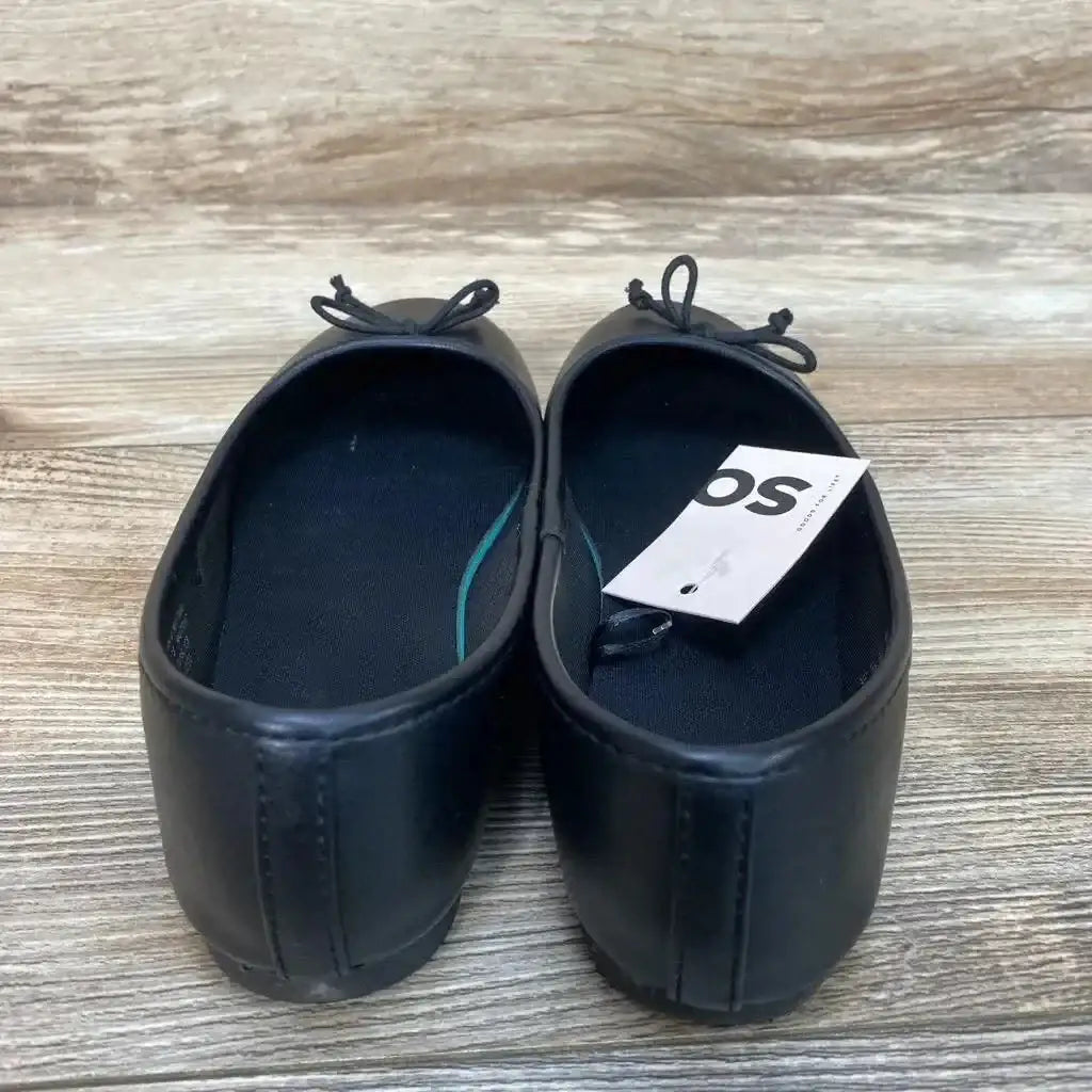 Rear view of New SO Pensacola black toddler ballet flats showing stitched heel seam and small bows, size 2Y on wood plank background