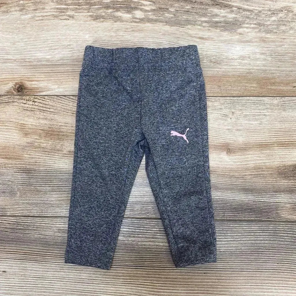 Top view of Puma leggings sz 6-9m showcasing dark gray heathered fabric and pink Puma logo on wood-grain background