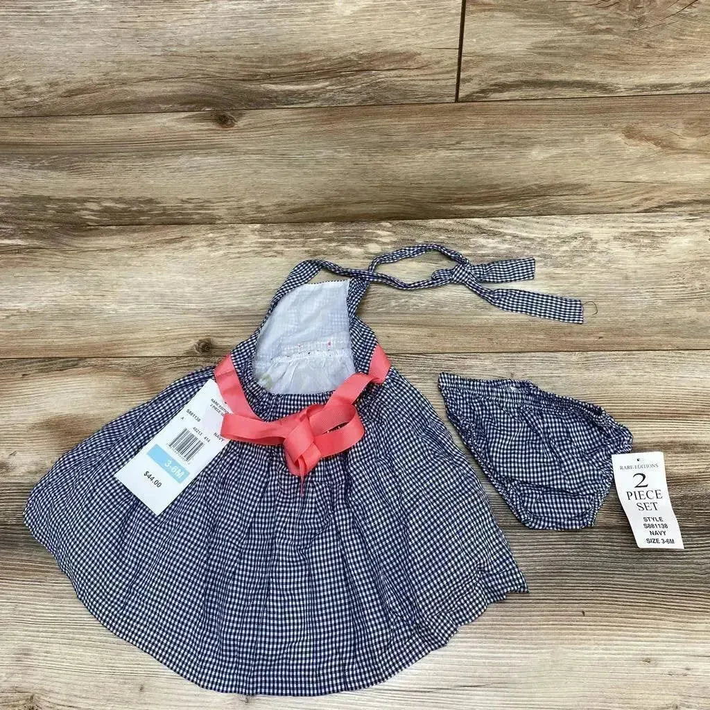 Flat lay of Rare Editions navy gingham 2-piece baby dress with pink bow and matching bloomers, size 3-6 months, on wood floor
